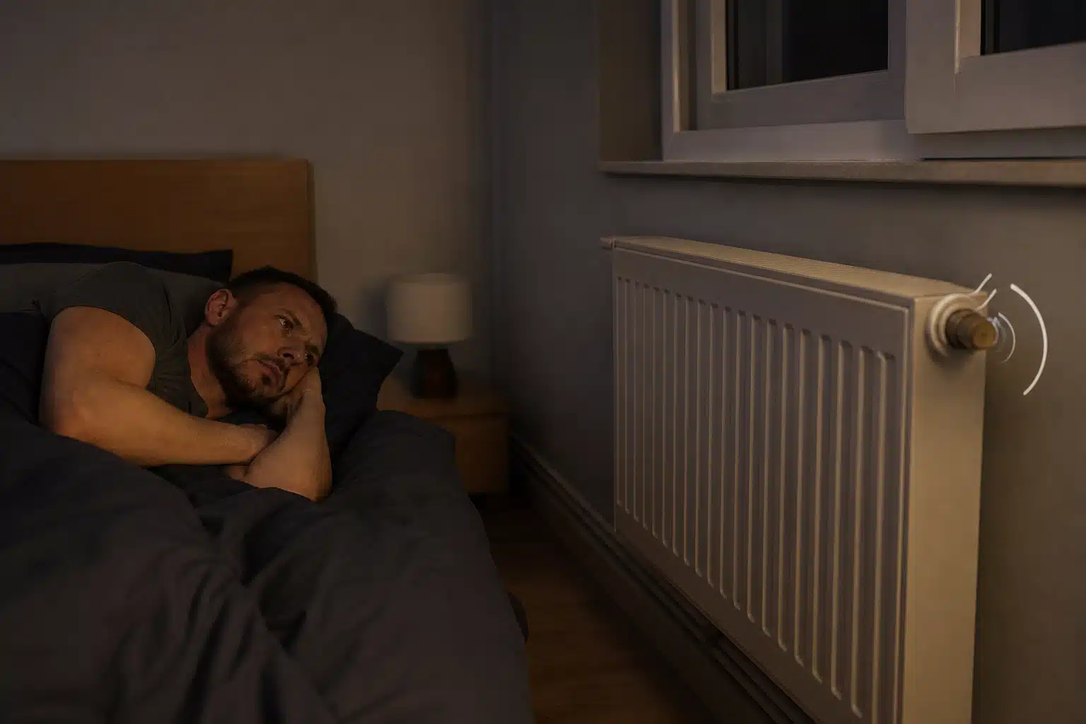 Homme endormi dans un lit près d'un radiateur